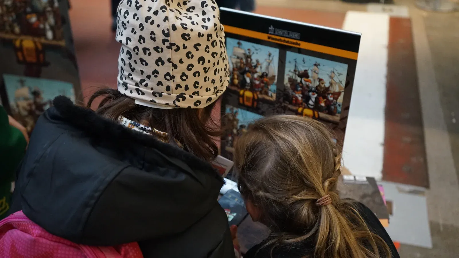 Zwei Kinder schauen auf ein Smartphone und probieren die Schnitzeljägerei-App im Medien-Parcours nach der Verleihung aus